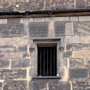 Nápis a okno, Na věžním průčelí je umístěna kamenná deska s latinským nápisem