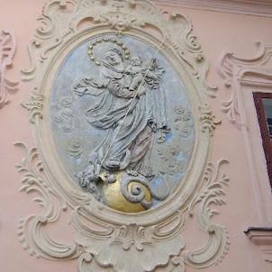 medailon s reliéfem Madony, Medailon je umístěn v štukové rokokové kartuši. Postava Madony částečně polychromovaná, zeměkoule zlacená, pozadí bledě modré.