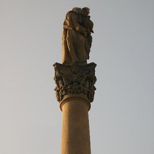Vrchol sloupu, Na vrcholu sloupu stojí socha sv. Anny Samotřetí s Ježíškem a Pannou Marií v náručí.